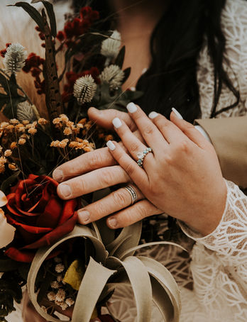A closeup of a wedding ring and bouquet.