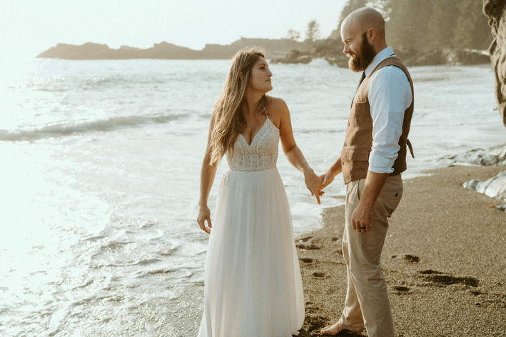 A couple doing portraits after wedding on a beach in tofino at sunset