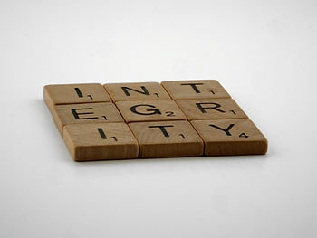 Wooden Scrabble tiles spell "INTEGRITY" on a white background. Each tile shows a letter with a point value, emphasizing honesty and trust.