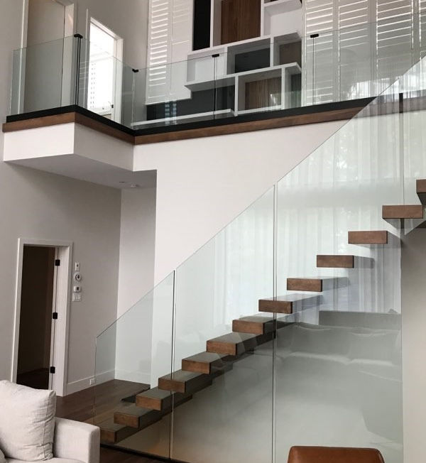 Escalier avec marche flottante fixé au mur avec garde-corps en verre avec stand off caché avec des plaquettes de bois.