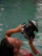 Fotografin blickt durch den Sucher einer Kamera mit großem Dome-Port für Unterwasseraufnahmen.