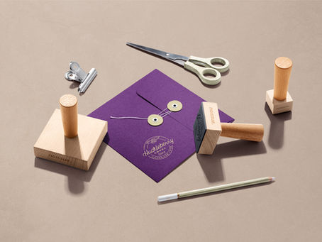 Mockup of the Huckleberry Creek Logo Rubber Stamp in Gold Ink on a Purple Envelope