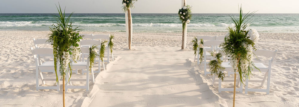 Wedding aisle made of sand and a floral arch.