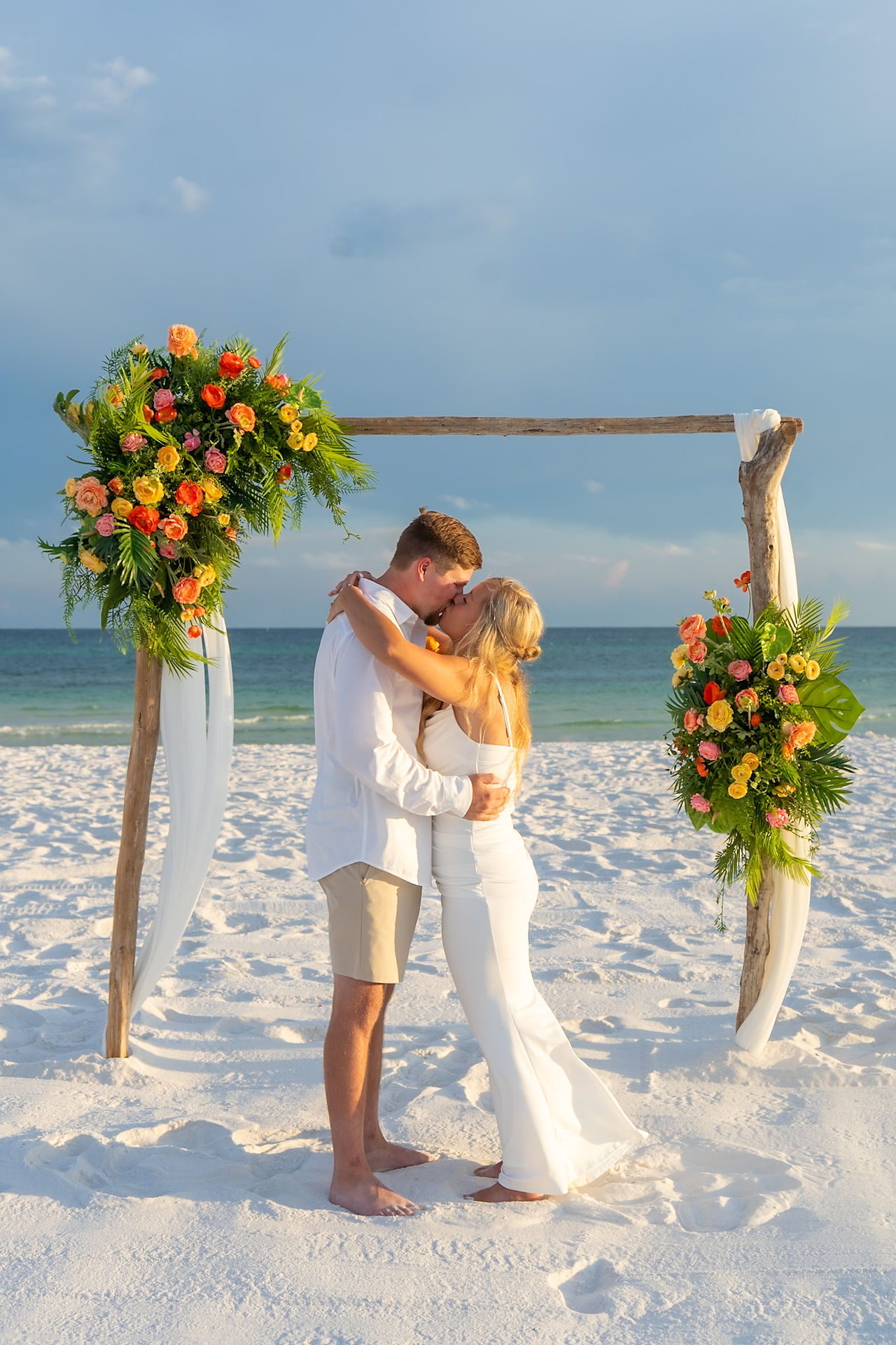 Bride and groom kissing surrounded by tropical flowers.
