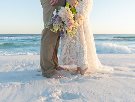 Couple standing on the beach in wedding attire after getting their Florida marriage license.