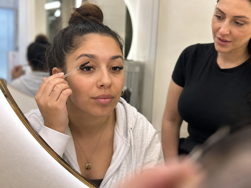 Client with fresh Russian Volume lashes checking the finished result while a lash technician explains aftercare in a London salon.