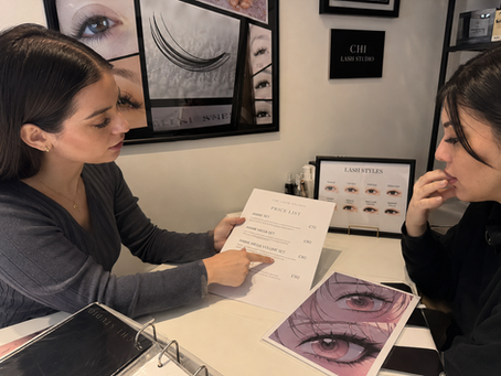 Lash technician discussing anime lash pricing with a client at a consultation table in a London salon.