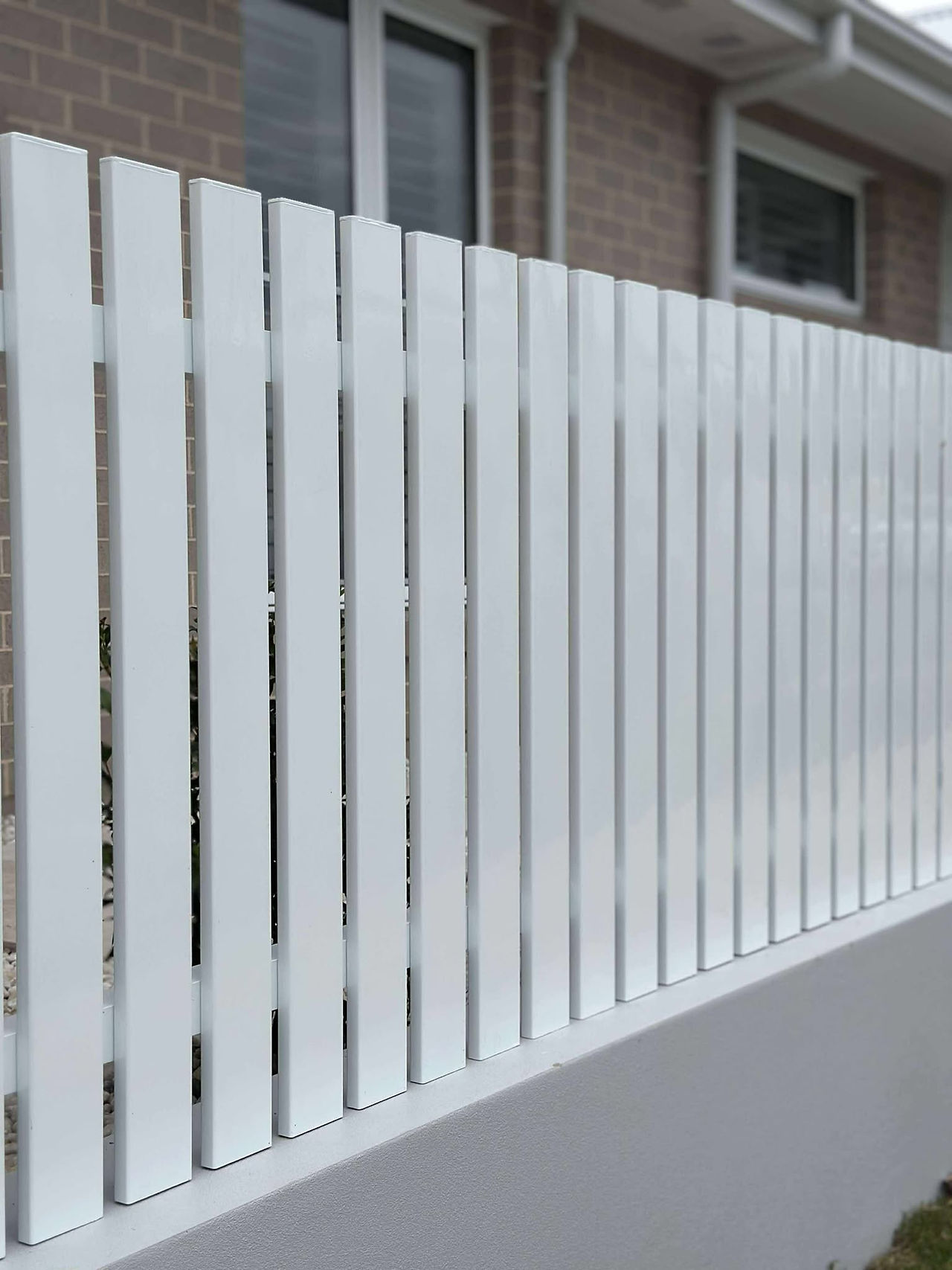 Vertical slat aluminium fencing with rendered post infills