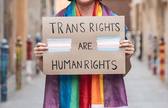 Transgender woman fighting for trans human rights at gay pride holding banner - People cel