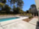 A Fiberglass Pool with Concrete Pool Deck & Stone Wall.