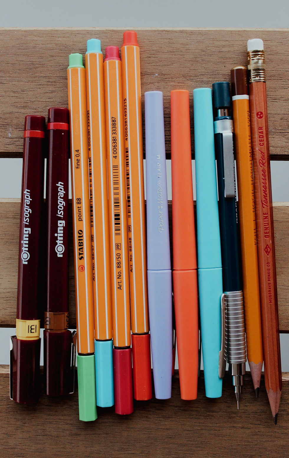 A handful of felt tip pens and technical pens, along with some pencils.