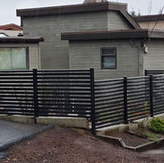 Black horizontal slat fence installation around residential property.