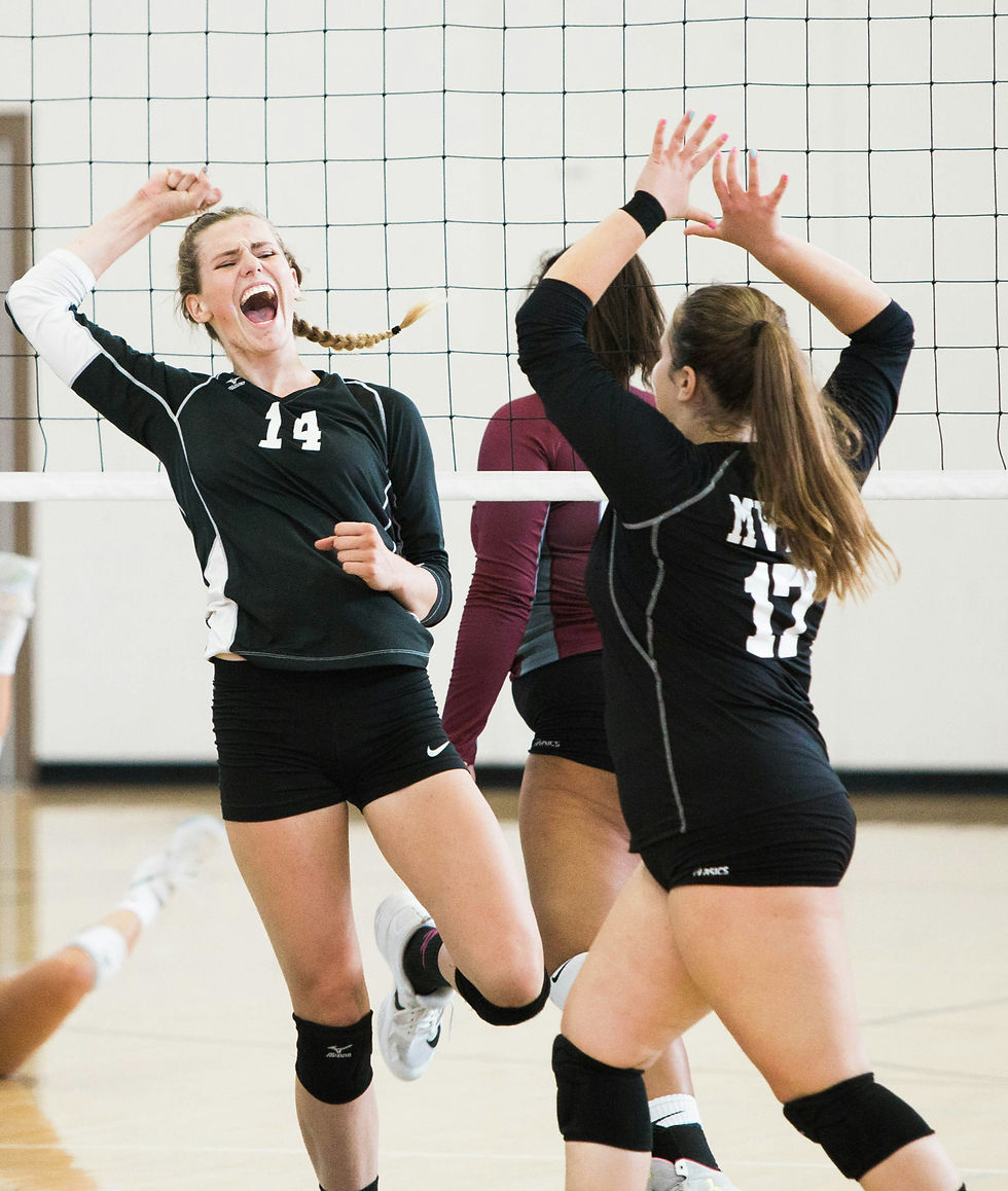 A group of girls volleyball players celebrating on the court after a great play.