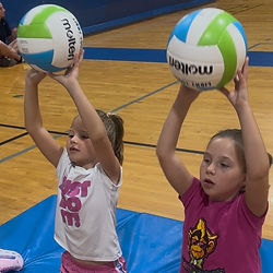 Athletes holding up volleyballs and beginning their volleyball journey.