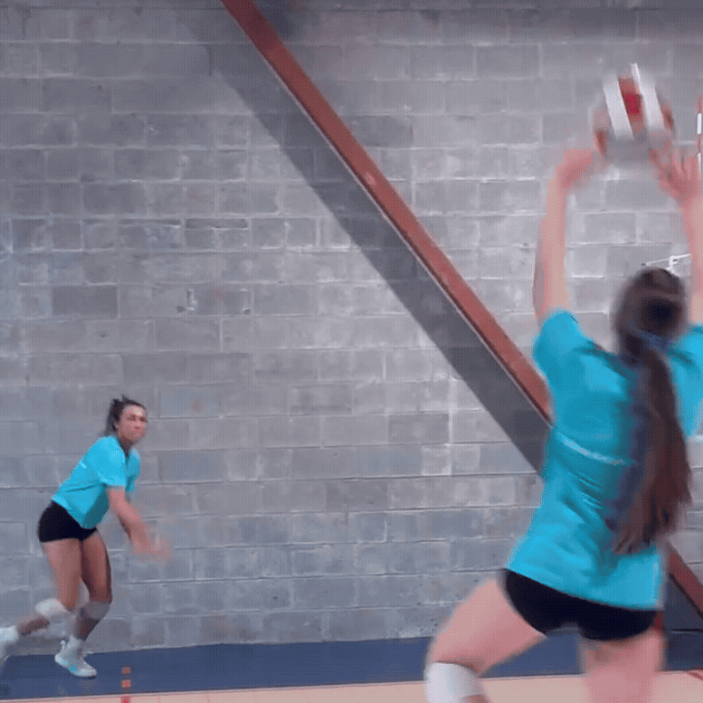 A girls volleyball attacking a volleyball from the outside.