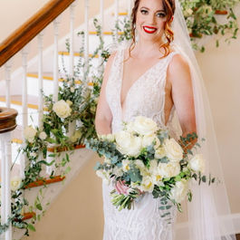 Smiling bride holding bouquet, wearing veil, standing on staircase; wedding flowers. jillheatonfloraldesign
