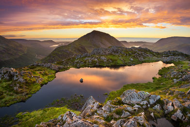 Beautiful sunset over Western Cumbria Coast seen from Haystacks Tarn in the Lake District_
