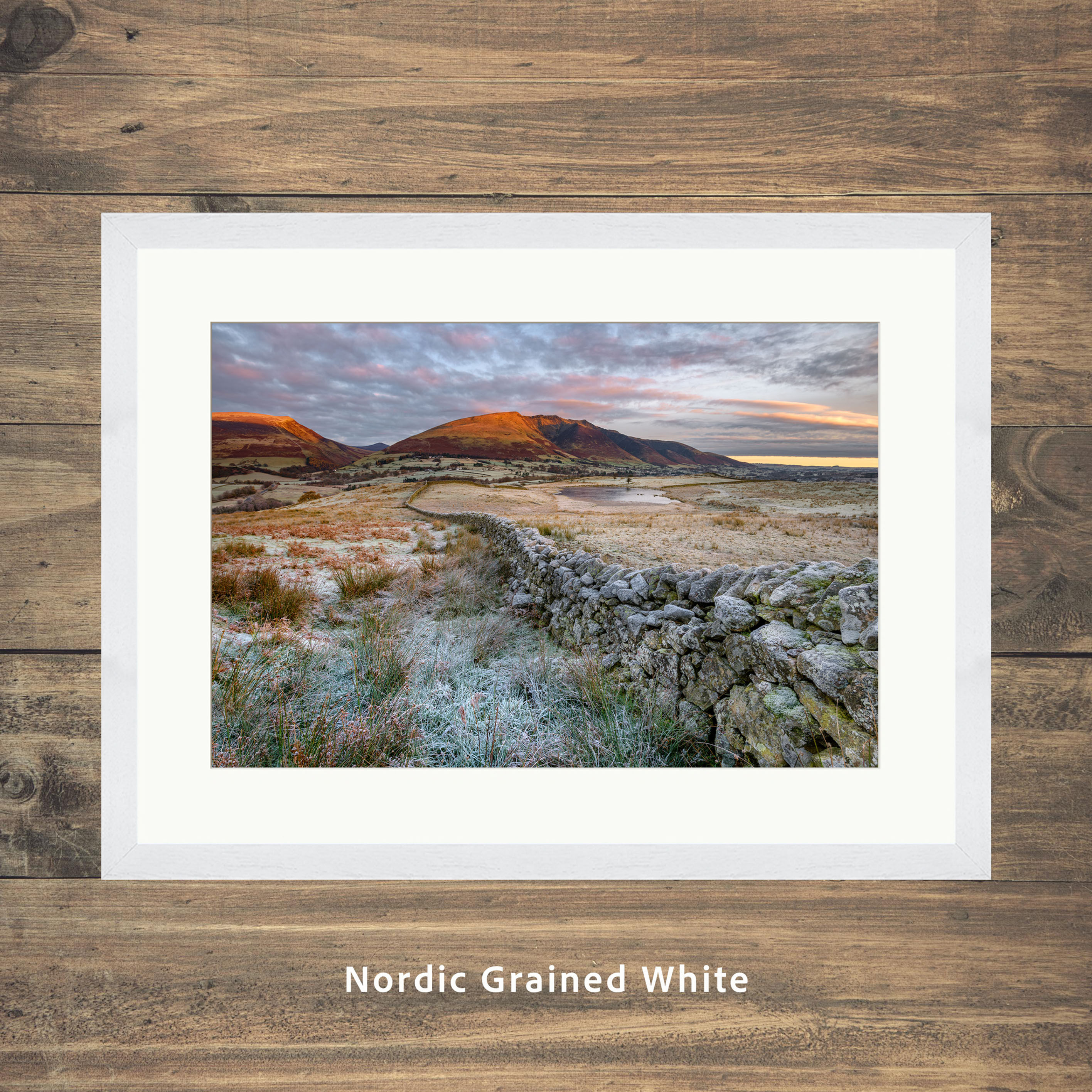 A frosty drystone wall leading into Blencathra in the winter morning light, seen from Tewet Tarn, Lake District, UK.