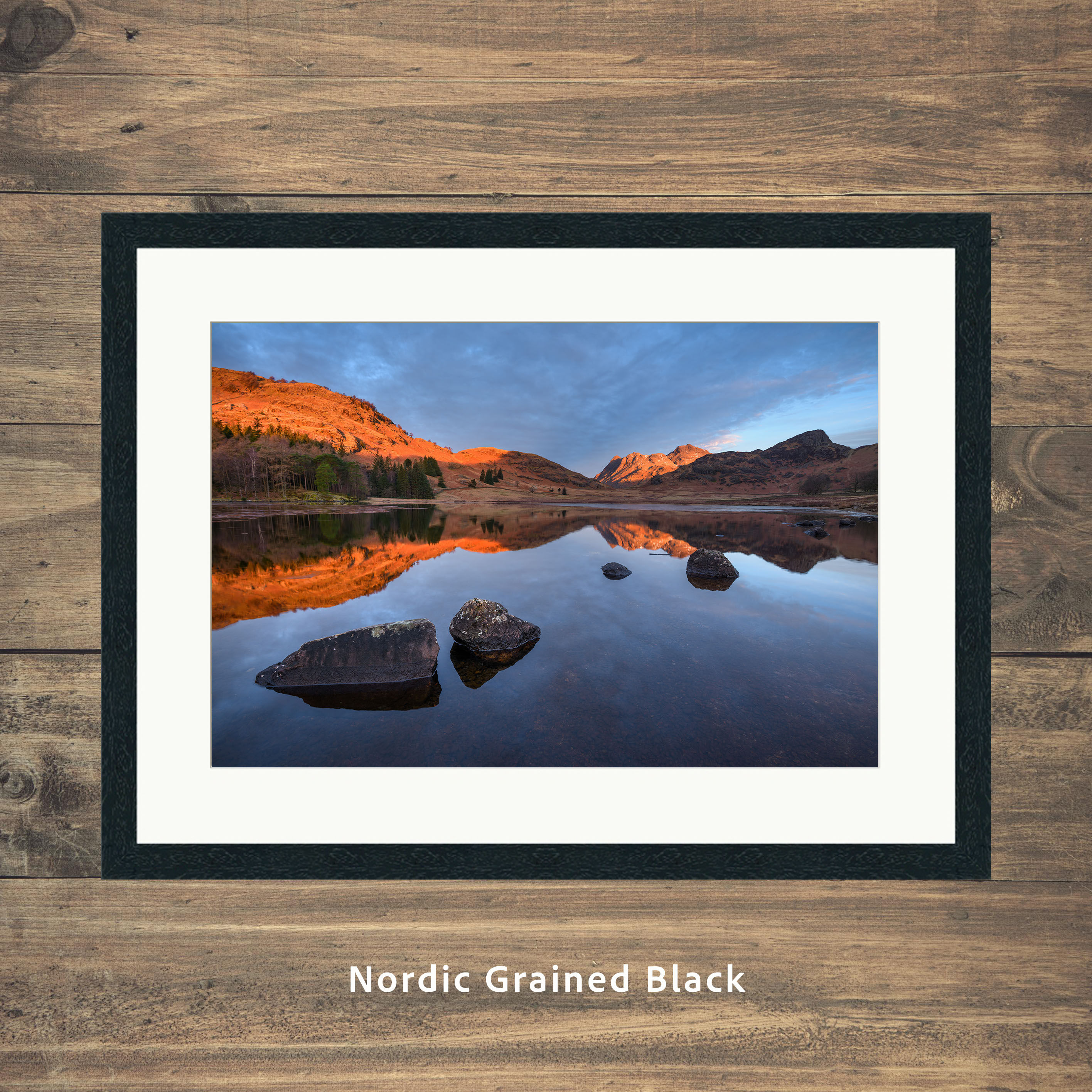 calm morning reflections at Blea Tarn, with golden light on The Langdale Pikes in The Lake District National Park, UK.