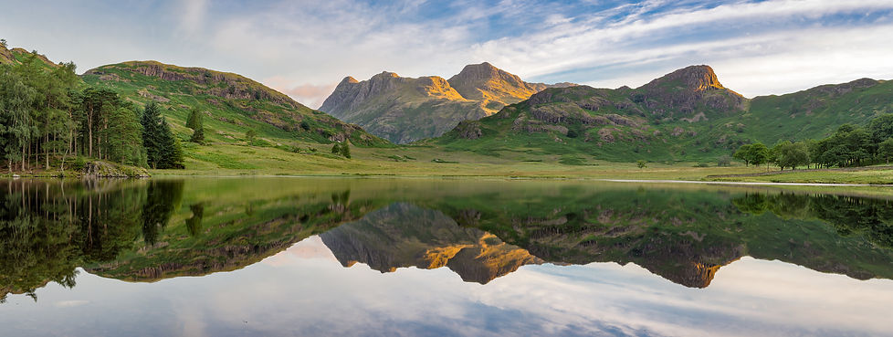 Panoramic view of Blea Tarn on a still morning with the Langdale Pikes reflecting in the water.