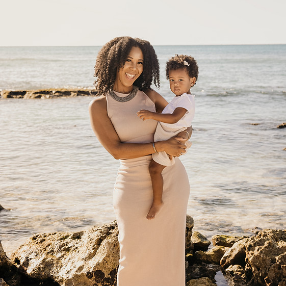 Chacha Alicia Miller holding baby girl standing near ocean