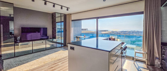 Custom kitchen island facing the television, living area and balcony.
