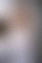 Smiling woman with long blonde hair in a white coat, arms crossed. Abstract brown and white background, calm and professional mood. Viewpoint Photography