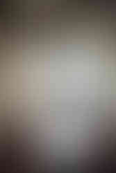 Bride and groom embrace in front of a grand stone building with arched windows. Her white dress and veil contrast with his black suit. Viewpoint Photography Edmonton