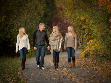 A family of four walking together on a pathway in a park.