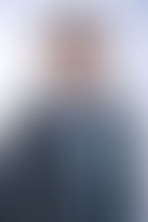 Smiling person in glasses and plaid suit jacket with light blue shirt and pocket square. Background is a soft white gradient. Viewpoint Photography Edmonton