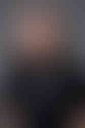 A person with long hair smiles, wearing a black "CPP Distribution" T-shirt. Gray background adds a neutral tone.