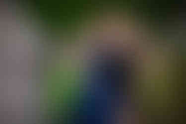 Two women in elegant dresses, one navy and one black, smile and pose outdoors near stonework and greenery. Mood is joyful. Viewpoint Photography Edmonton