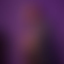Man in a blue suit plays saxophone on stage under purple lighting, beside a microphone. The mood is focused and jazzy. Viewpoint Photography Edmonton