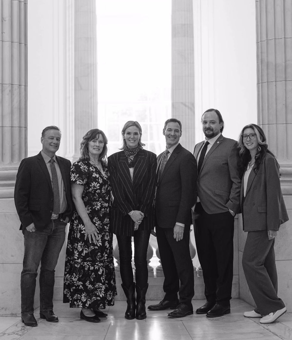 Six smiling members of the American Wild Horse Conservation team pose on Capitol Hill between tall columns in a black-and-white formal group portrait.