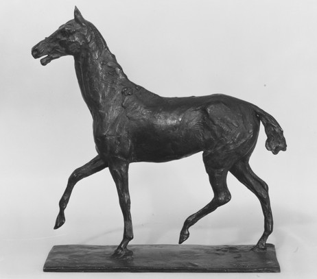 A bronze horse sculpture depicts a walking motion on a textured base. The setting is neutral, highlighting the dark, realistic details. Horse Walking is an equine sculpture by Edgar Degas as featured in EquuStyle Art & Travel magazine.