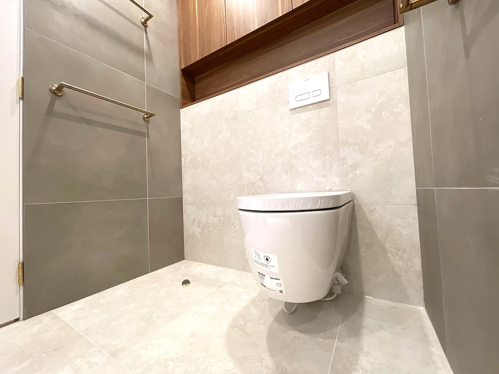 Modern bathroom renovation in Point Grey Vancouver by Grand Renovations featuring wall-mounted toilet, beige tiles, and brass towel bar in a sleek minimal design