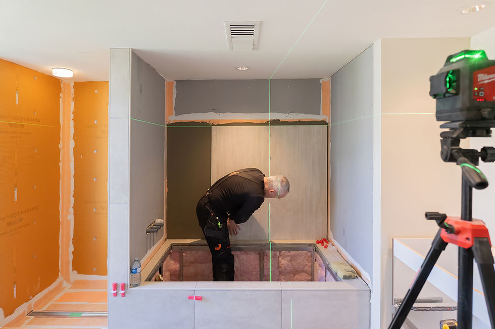 Grand Renovations installer precision setting large format wall tile over bathtub deck using laser level
