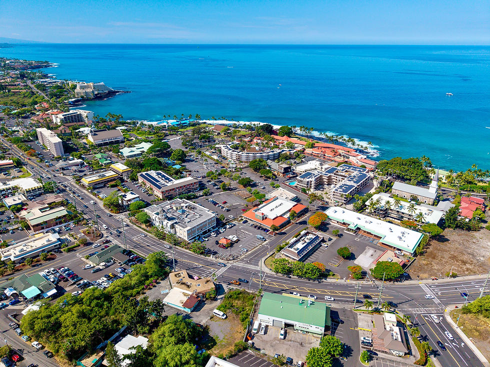 Aerial view of downtown Kona showing Kuakini Highway, Alii Drive, commercial buildings, hotels, and the Kona coastline.
