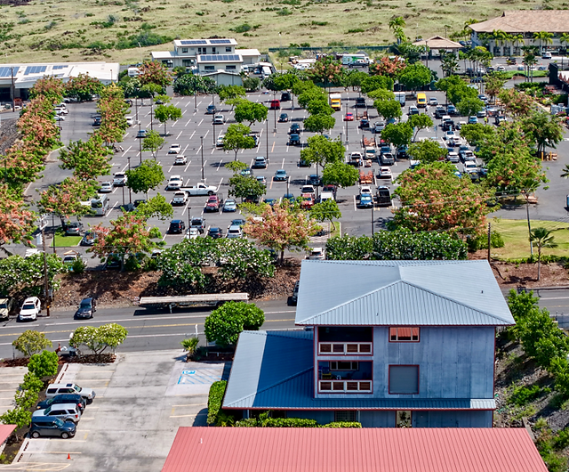 Aerial view of a busy parking lot filled with many cars and trees.