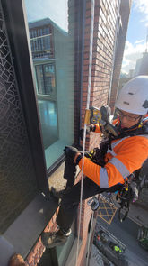 Worker in safety gear rappelling down a building