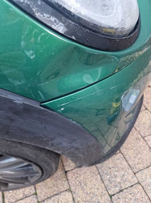 car body dent on the front side of green car