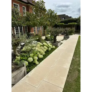 Long paved garden pathway with light stone slabs and planted borders