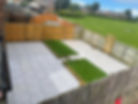 gray tiled flooring with two rectangular patches of artificial grass bordered by wooden frames