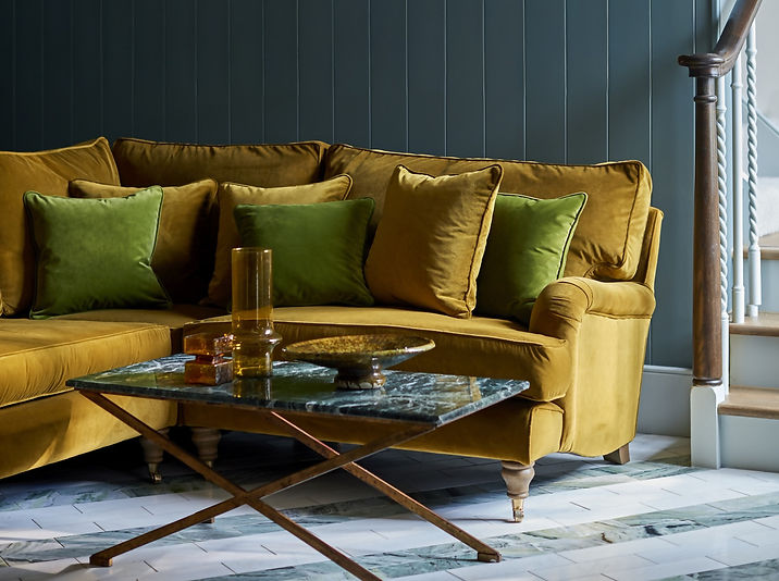 Upholstered yellow sectional sofa with green cushions and coffee table