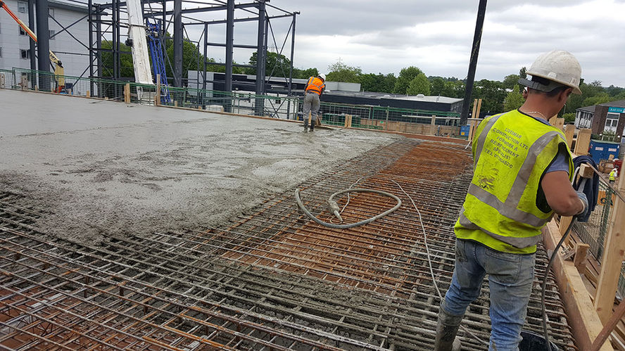 Workers smoothing freshly poured concrete on a building rooftop