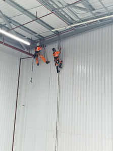 Two workers performing rope access inside building