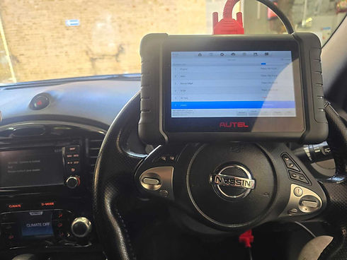 A diagnostic tool mounted on a car's steering wheel, displaying vehicle data on the screen