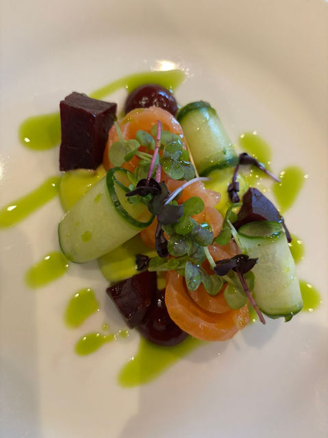 Plated salad with cucumber, carrot, beet, and green dressing