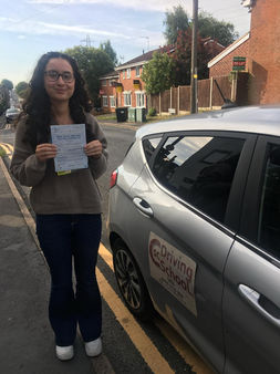 young woman after passing driving test, holding a certificate and smiling at the camera
