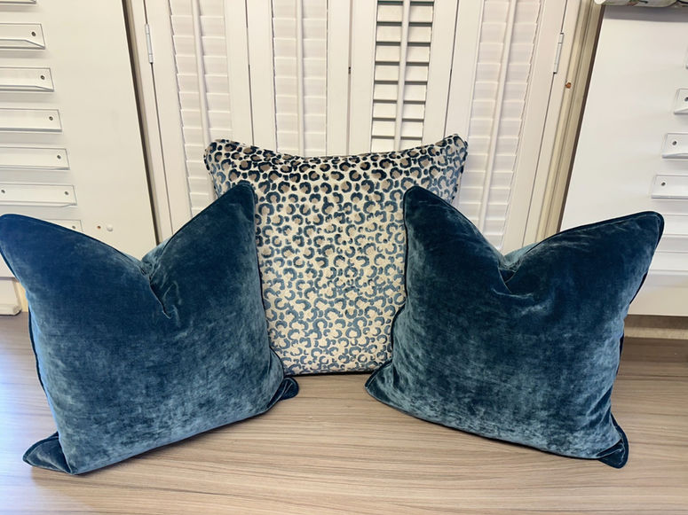 Two teal velvet pillows, one patterned